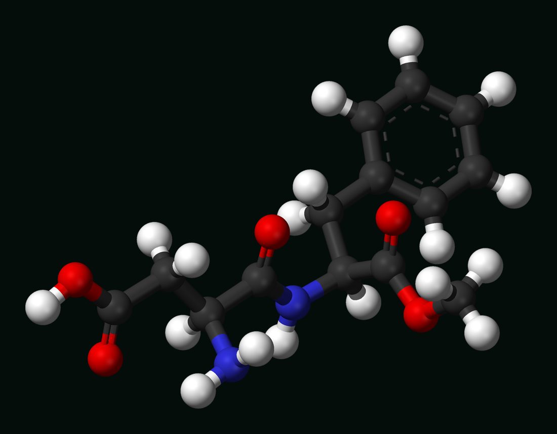 Ball and stick molecular model of aspartame, with carbon in dark grey, oxygen in red and nitrogen in blue