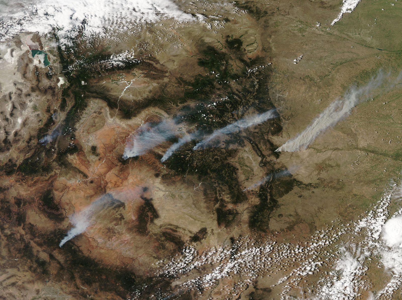 MODIS satellite view of the western United States with dozens of red fire-detection marks and pale smoke plumes drifting east across several states