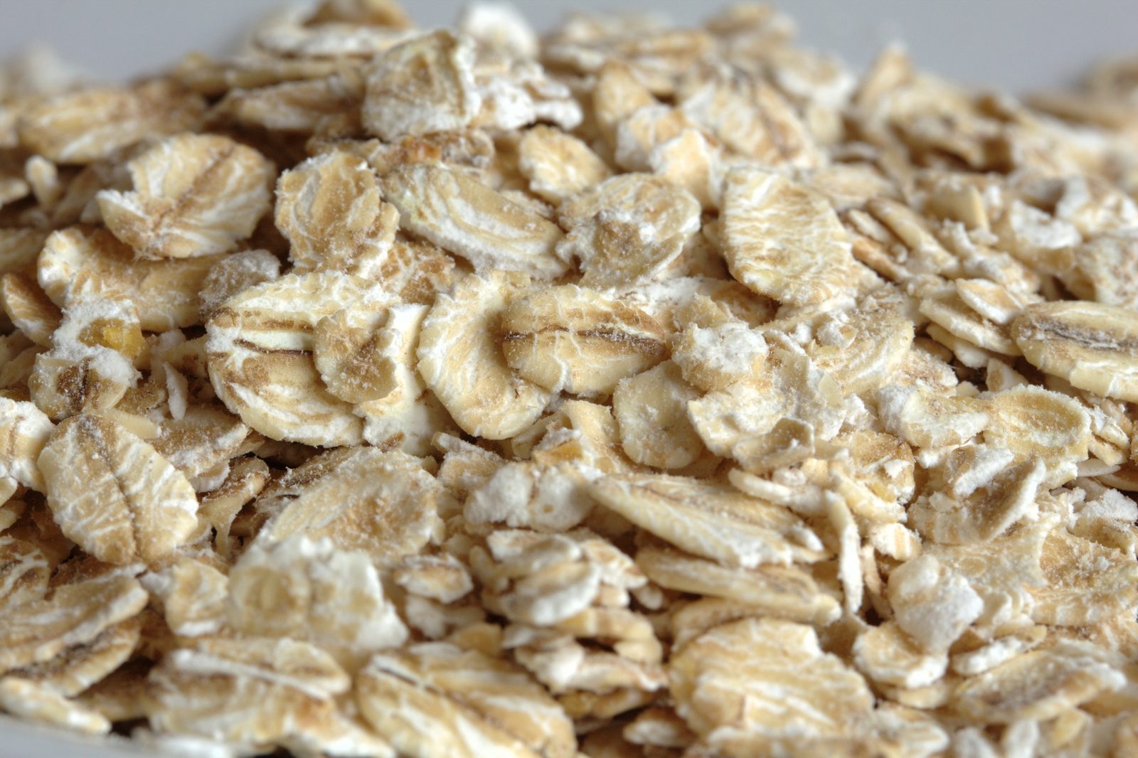 A close macro of rolled oats heaped on a pale surface