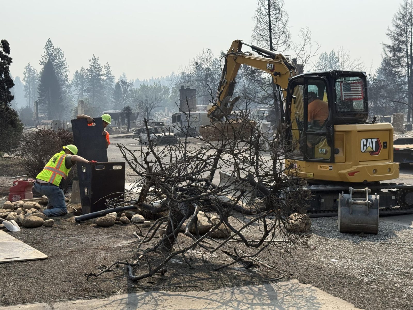A burned hillside in eastern Washington with a city crew and an excavator working among charred trees