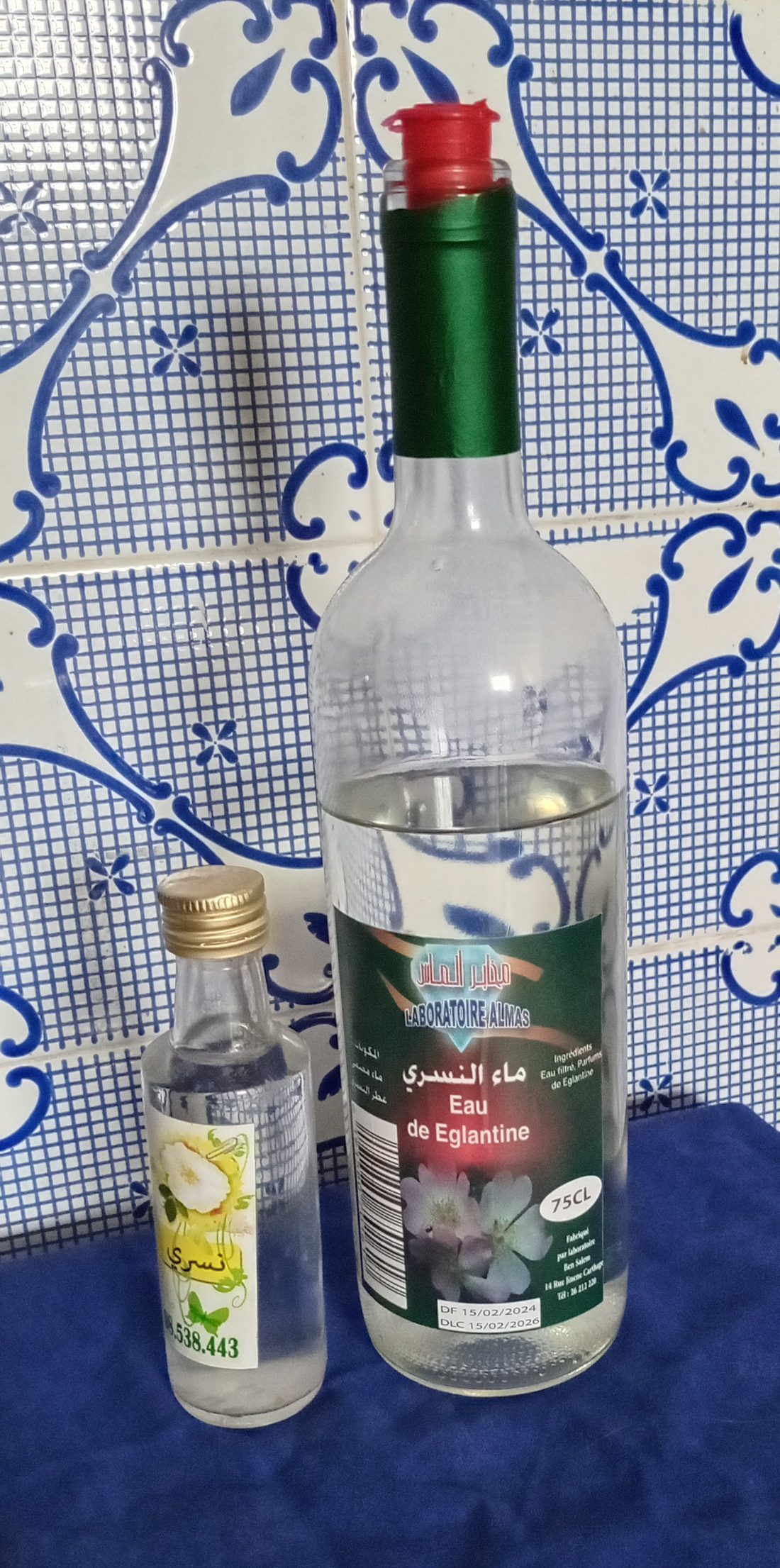 A glass bottle and a small jar of a plant-derived skincare preparation on a tiled surface