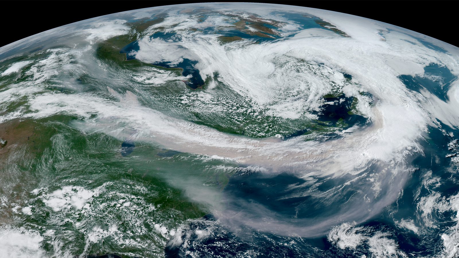 Geostationary satellite view of North America with a broad grey-brown smoke layer drawn from the Great Lakes across the northeast to Atlantic Canada